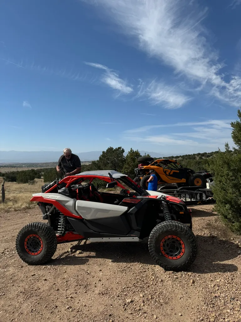 Someone leaning over the cockpit of a red and white Can-Am Maverick